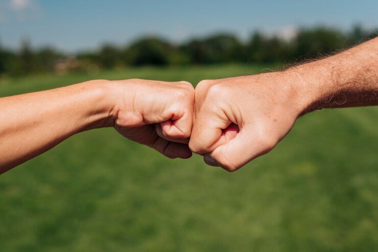 close-up-two-fists-hitting-outdoors_23-2148247196